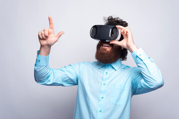 Photo of bearded man in blue shirt wearing VR glasses and touchi