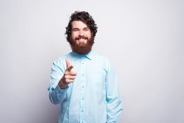 Photo of cheerful bearded man in blue shirt pointing at the came