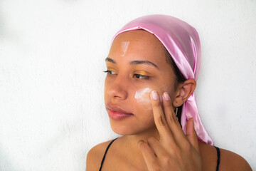 Woman with pink scarf using face cream