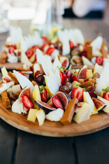 food snack cheese strawberry figs sliced ​​on a board on a dark wooden table