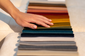 Fototapeta premium The woman chooses the fabric on the sofa. Textile industry background. Tissue catalog