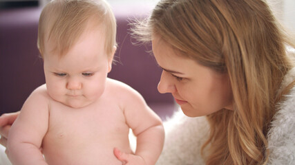 Mother playing with child. Naked baby girl learning play