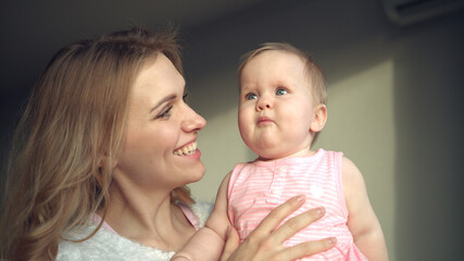 Cheerful mother playing with baby. Woman have fun with toddler girl