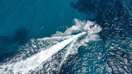 Aerial photo of woman operating jet ski cruising in low speed in deep blue crystal clear waters