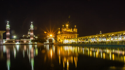 Fototapeta na wymiar reflection of golden temple at night on water surface of nearby lake