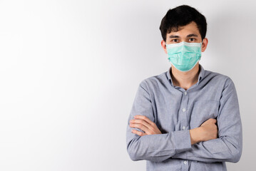 young Asian man standing arms crossed wearing green sanitation mask on face on white background in studio and looking at the camera. COVID-19 health care and safety concept.