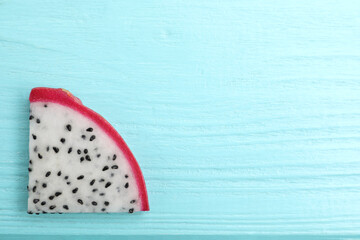 Slice of delicious dragon fruit (pitahaya) on light blue wooden table, top view. Space for text