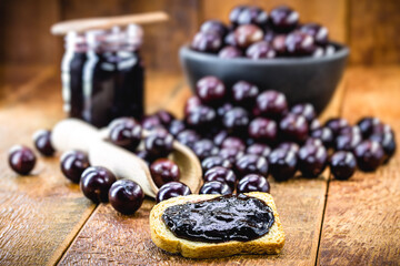 toast with grape jam, on rustic wooden table. Jabuticaba, exotic Brazilian fruit, used in cooking, as a sweet.