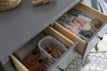 Open cabinet drawers with clothes and different items in child room