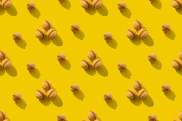 A repeating pattern of walnut cookies on a yellow background. Seamless texture
