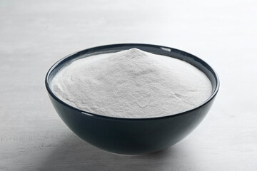 Baking soda in bowl on white wooden table