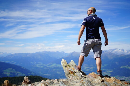 Hiker watching the valley above from the top of the mountain on a summer day