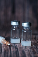 Close up of coronavirus vaccine and syringe on black background