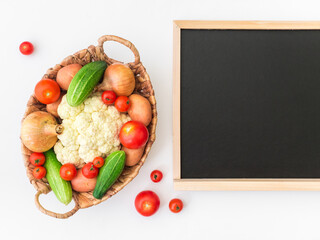 Fresh farm vegetarian and vegan vegetables in wicker basket and blackboard on white background. Healthy food supermarket banner. Zero waste concept. Copy space