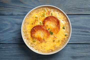 Tasty homemade french onion soup on blue wooden table, top view