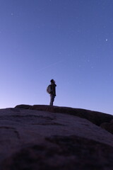 Young hiker watching shooting star pass by on top of mountain in the early morning before sunrise