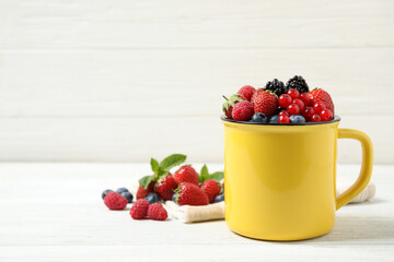 Mix of ripe berries on white wooden table. Space for text