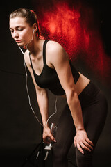 Slim sports woman with earphones on the black studio background