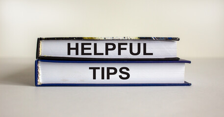 Books with text 'helpful tips' on beautiful white table. White background. Business concept. Copy space.