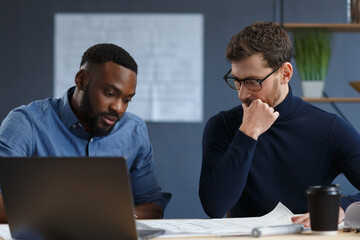 Multiracial engineer team working in office with blue prints and architect equipment...