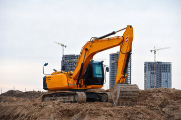Obraz premium Excavators during earthworks at construction site. Backhoe the digging pit for construct building foundation. Paving out sewer line. Construction machinery for excavating, loading, lifting and hauling