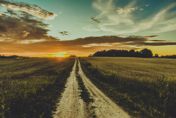 Obraz premium Sunset or sunrise and the road through the field