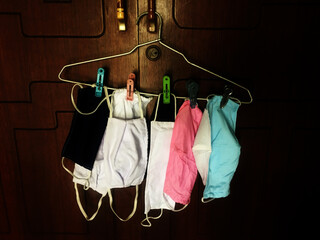 Cold and gloomy photo of face masks from hanging on a wooden hanger in a room during the world pandemic COVID-19