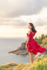 Portrait of Young Asian Woman in a beautiful red dress standing at the edge of cliff in the top mountains. Fashion model, bride or pre-wedding concept.