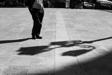 Fototapeta na wymiar Sicilian man in a square with his hands in his pockets with elongated shadow in black and white.Black and white. Shadow and light, man silhouette