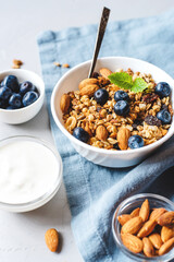 Baked granola with yogurt and blueberries on a gray table.