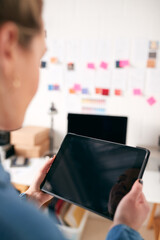 Close Up Of Businesswoman Using Tablet Computer In Studio Of Start Up Creative Business
