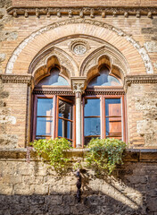 Fototapeta na wymiar Window with a column in the Venetian style in a medieval building in San Gimignano, Italy