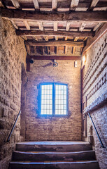Staircase, window, corridor and ceiling with wooden beams in medieval tower in San Gimignano, Italy