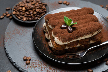 Classic tiramisu dessert on ceramic plate on concrete background