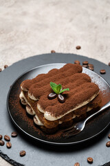 Classic tiramisu dessert on ceramic plate on concrete background