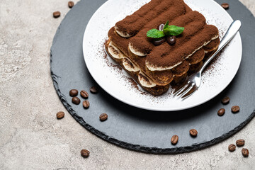 Classic tiramisu dessert on ceramic plate on concrete background