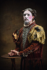 Great posing. Young man as Johann Bach isolated on dark green background. Retro style, comparison of eras concept. Beautiful male model like historical character, great music composer, old-fashioned.