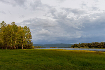 Obraz premium The rays of the setting sun glide along the bank of the Yenisei, on the beginners to paint with autumn colors of grass and trees.