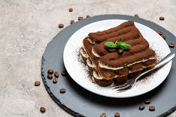 Classic tiramisu dessert on ceramic plate on concrete background