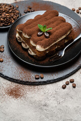 Classic tiramisu dessert on ceramic plate on concrete background