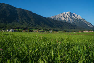 Fototapeta na wymiar Panoramic view on traditional Austrian village with alpine rocky mountain range background, Wildermieming, Mieminger Plateau, Tirol, Austria