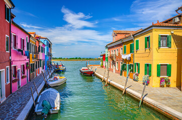 Fototapeta na wymiar Burano island with colorful houses and buildings on embankment of narrow water canal with fishing boats and view of Venetian Lagoon, Province of Venice, Veneto Region, Northern Italy. Burano postcard
