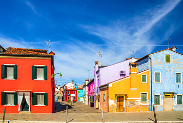 Burano island colorful houses. Multicolored buildings on fondamenta embankment of water canal and narrow street, blue sky in sunny day, Venice Province, Veneto Region, Northern Italy. Burano postcard
