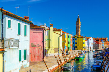 Fototapeta na wymiar Burano island with colorful houses on fondamenta embankment of narrow water canal with boats and Bell tower of San Martino church, Venice Province, Veneto Region, Northern Italy. Burano postcard