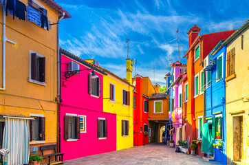 Fototapeta na wymiar Colorful houses of Burano island. Multicolored buildings in small yard, blue sky background in sunny summer day, Venice Province, Veneto Region, Northern Italy. Burano postcard