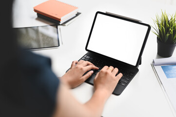 A close-up image of a woman is using a computer tablet at the white working desk.