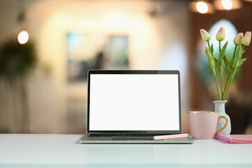Fototapeta premium Montage computer laptop with a white screen is putting on a counter bar with a tulips jar and coffee cup.
