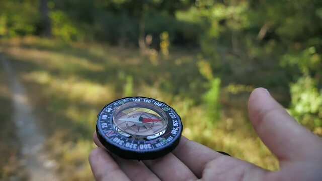 Extreme close-up of a transparent modern compas in the forest background. Concept of travel, adventure, expedition