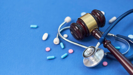 Wooden judge gavel with drugs on table. Space for text. Medical concept. on a blue background....