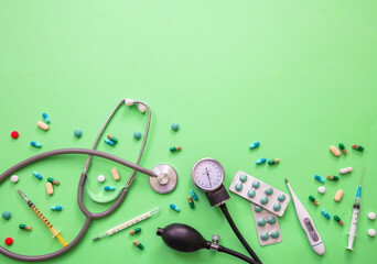 Blood pressure meter, medical stethoscope and medicine on pastel green background, close up view.